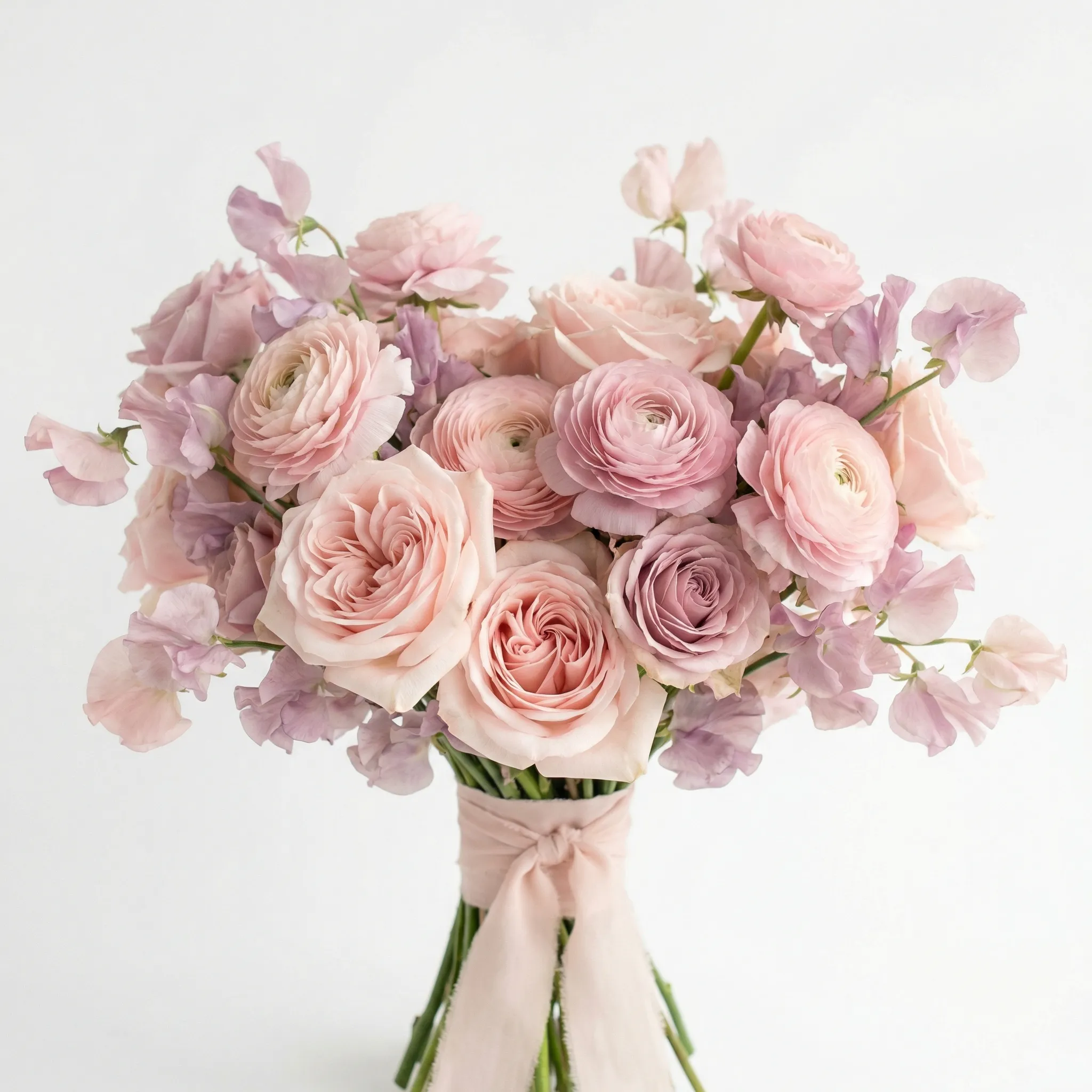 Romantic bridal bouquet of garden roses, ranunculus, and sweet peas in blush and mauve tones, soft studio lighting on white background